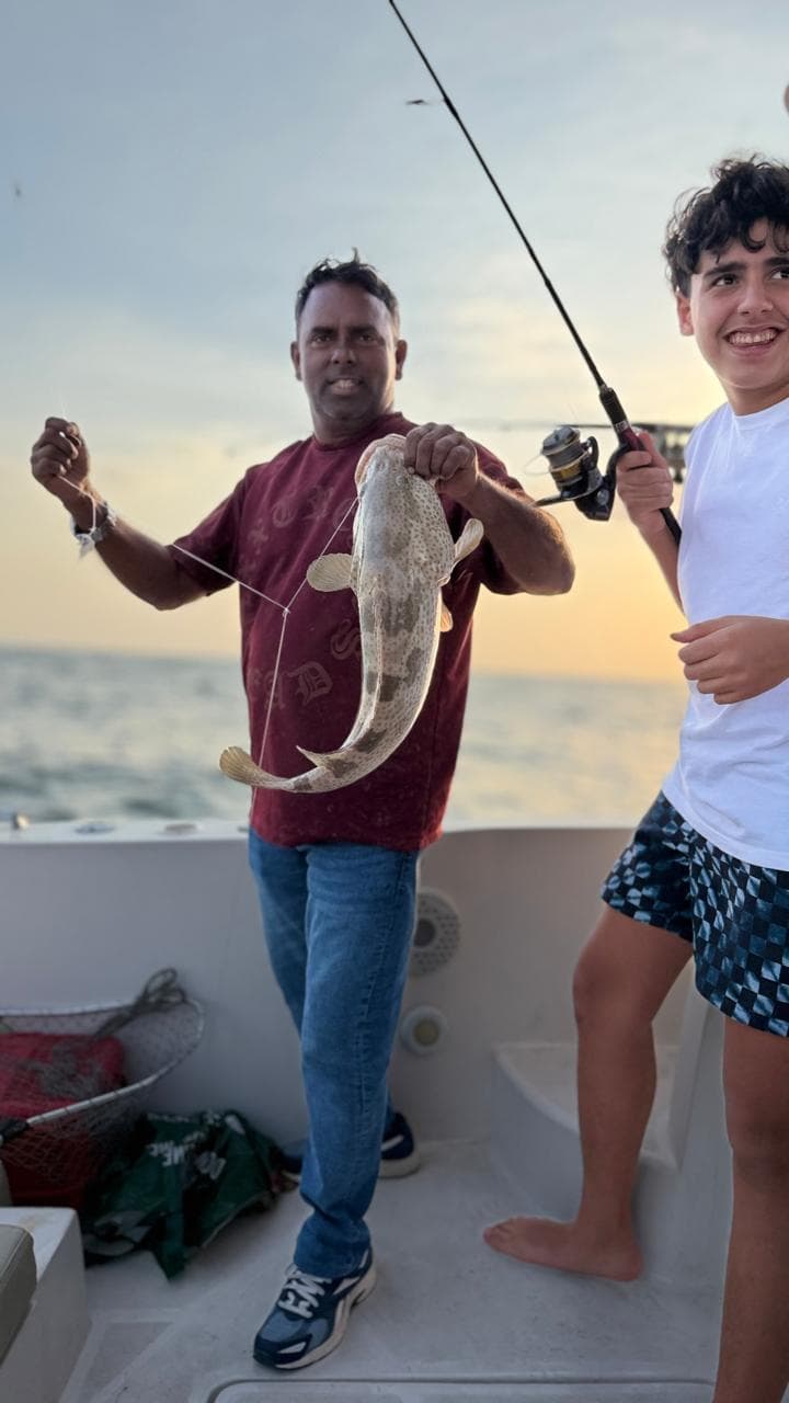 Guests holding a grouper caught on a XTASEA charter at sunset