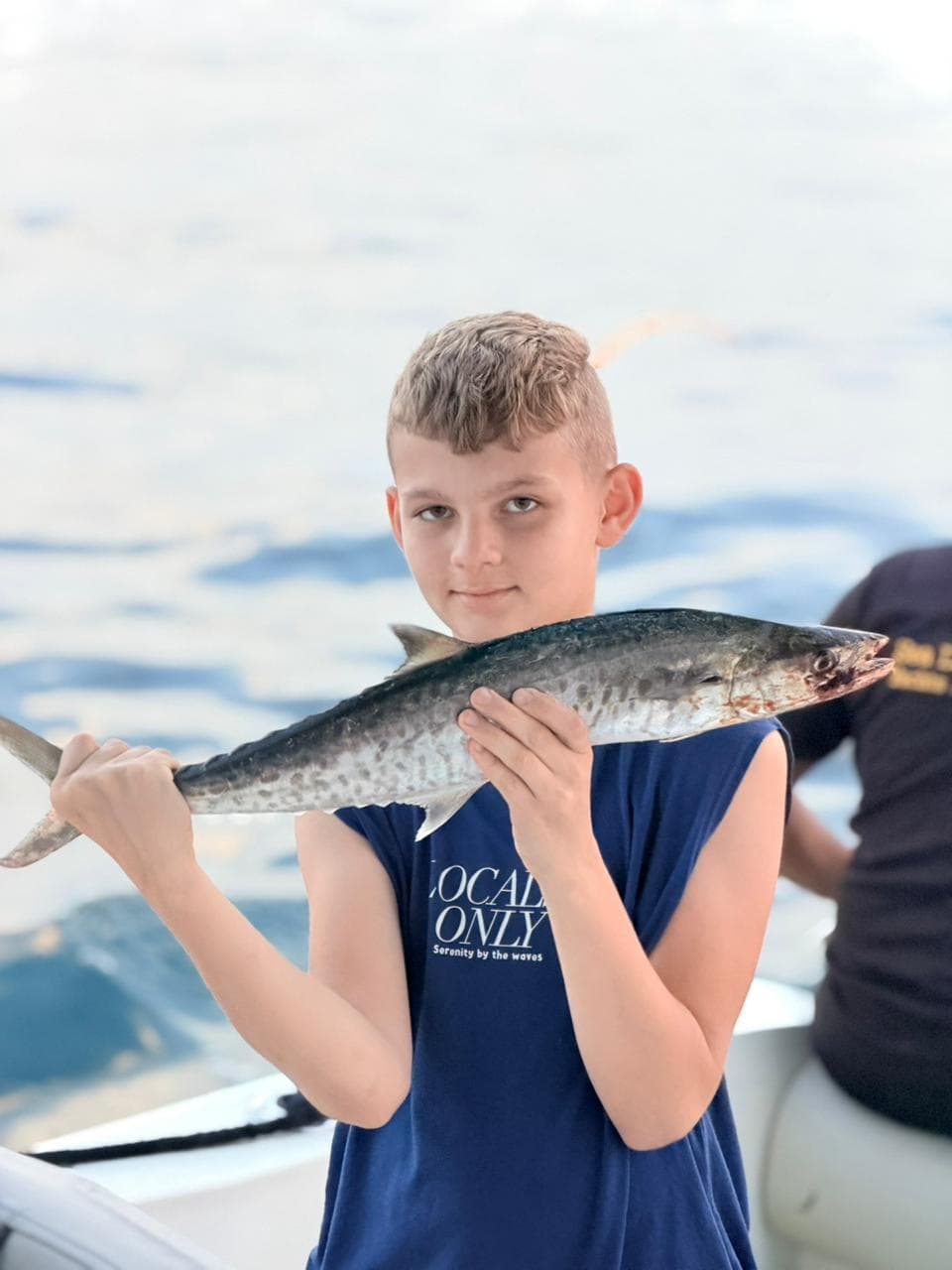 A young angler proudly holding a king mackerel