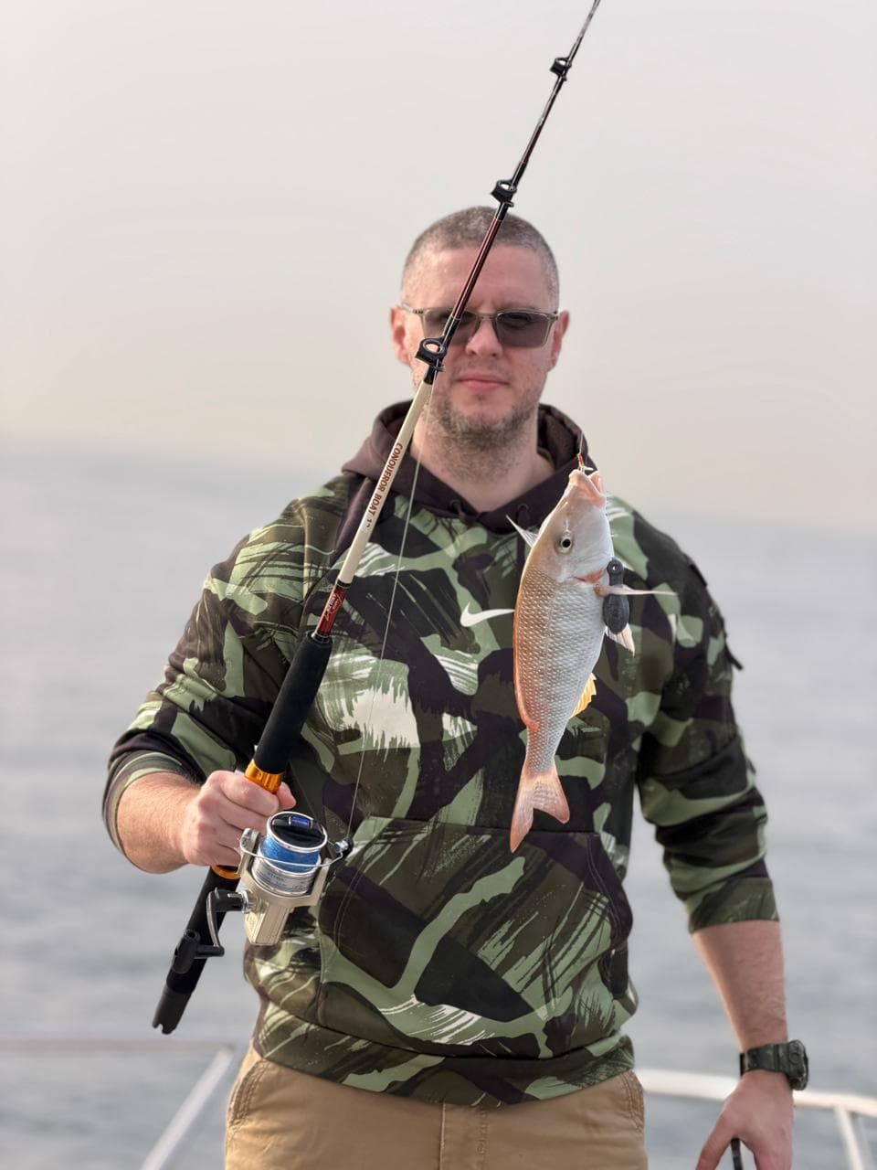 Angler with a snapper on the line at golden hour